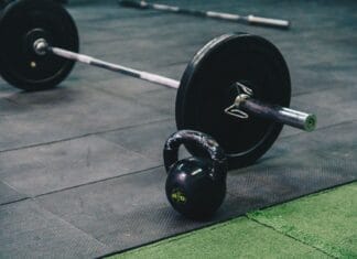 Trening siłowy dla początkujących: jak bezpiecznie zacząć ćwiczyć na siłowni Sztanga i kettlebell leżące na podłodze siłowni